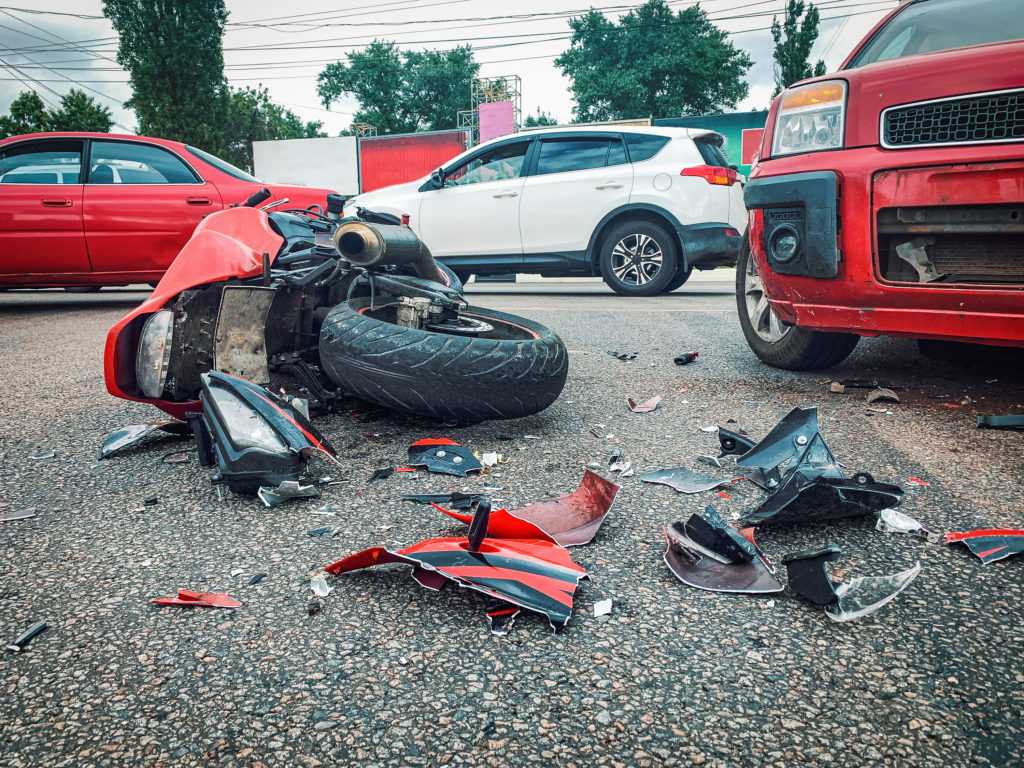 Motorcycle bike accident and car crash, broken and wrecked moto on road